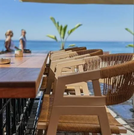 Seafront café terrace with wooden tables and rattan chairs looking out to the sea